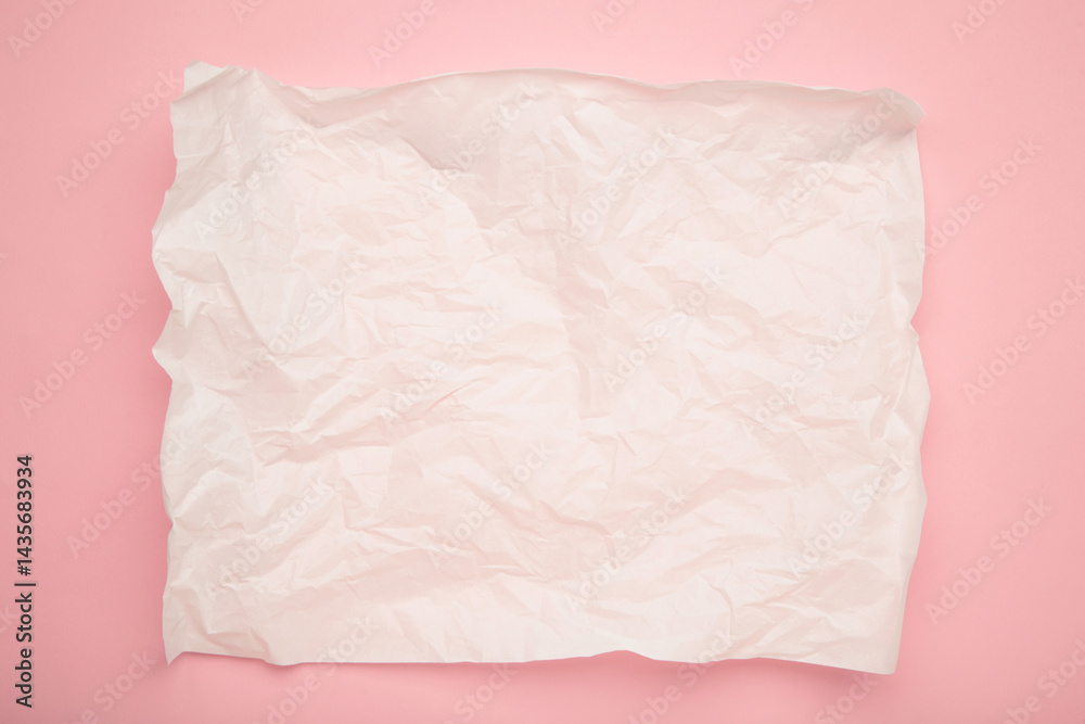 Obraz premium Crumpled piece of white parchment or baking paper on pink background. Copy space for text and design element.