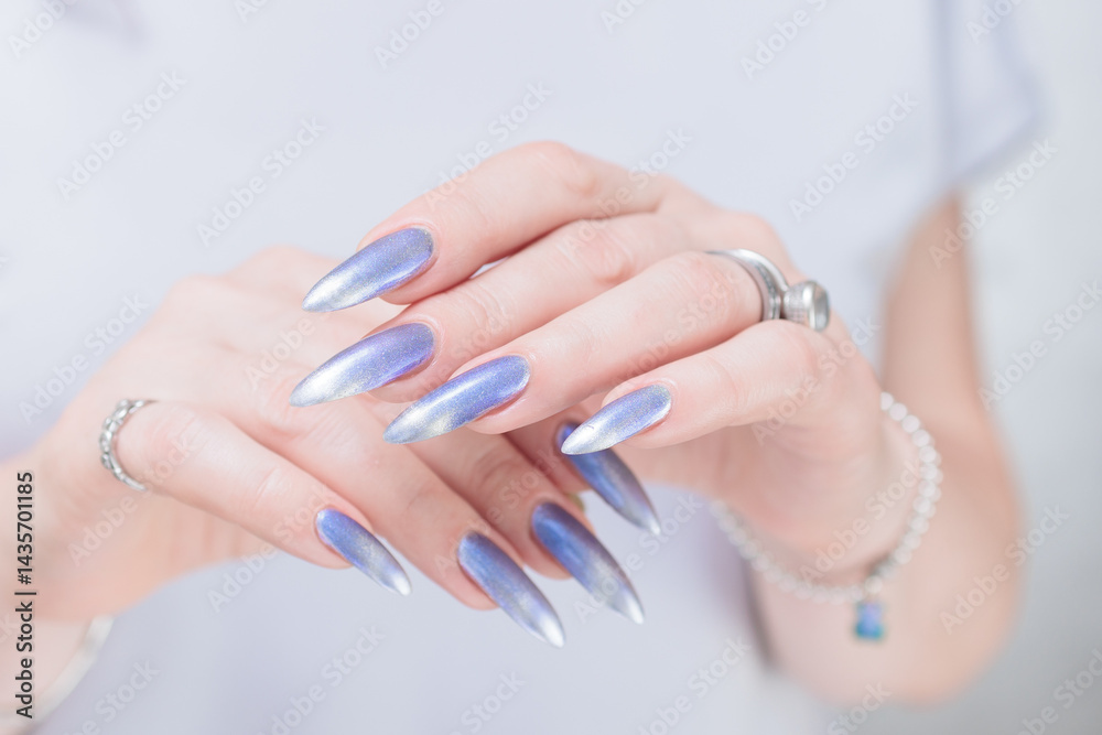 Female hand with long nails and bright light blue and silver manicure Female hand with long nails and bright light blue and silver manicure