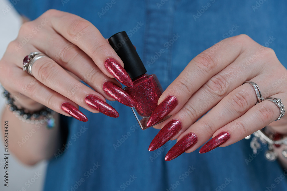 Obraz premium Female hand with long nails and a bright red manicure