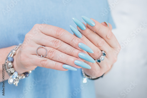Woman's beautiful hand with long nails and light baby blue manicure