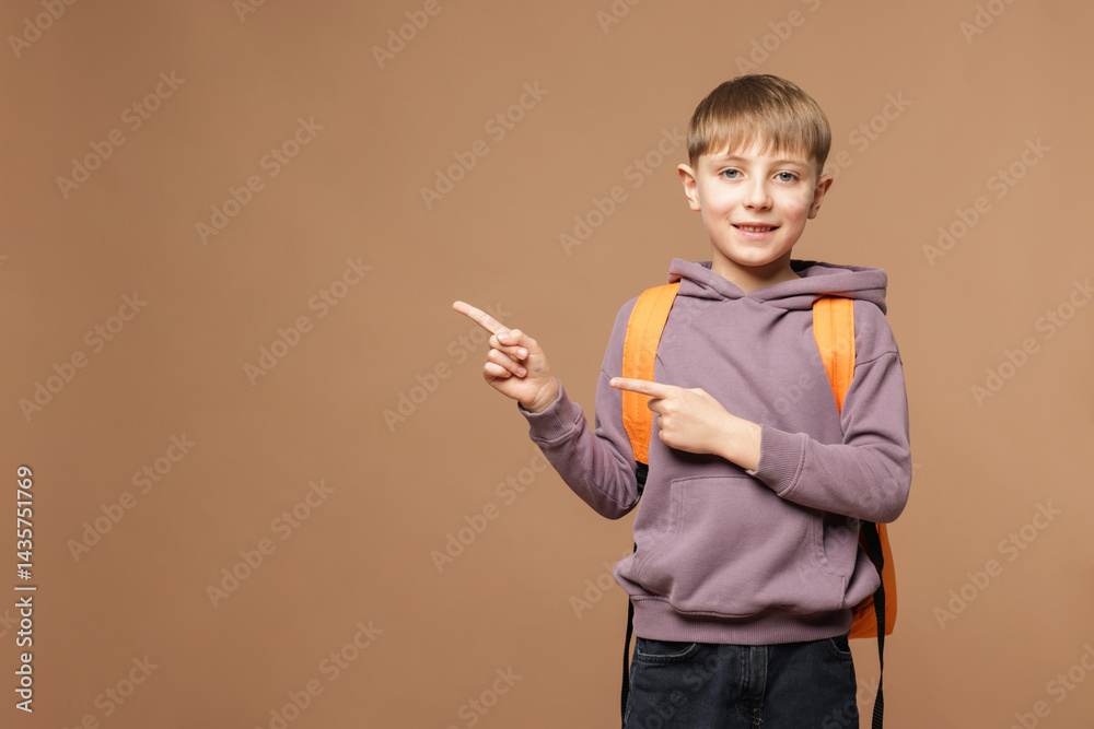 Cute schoolboy with backpack pointing at something on brown background, space for text Cute schoolboy with backpack pointing at something on brown background, space for text