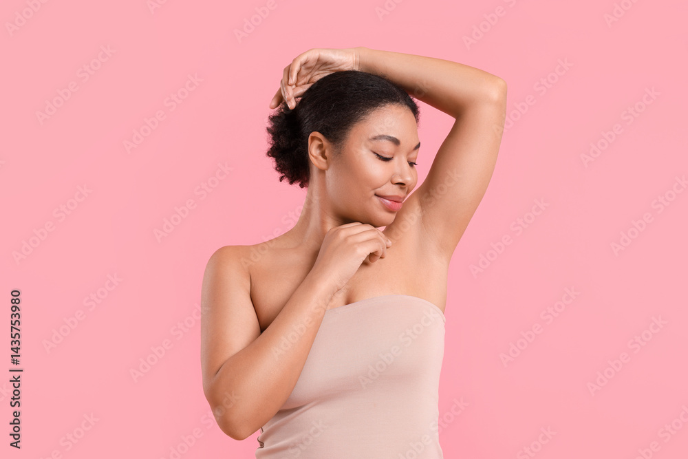 Woman showing hairless armpit after epilation procedure on pink background