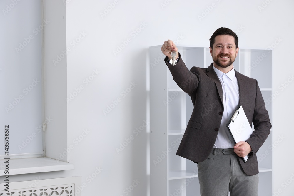 Real estate agent holding key with house shaped keychain and clipboard indoors, space for text Real estate agent holding key with house shaped keychain and clipboard indoors, space for text