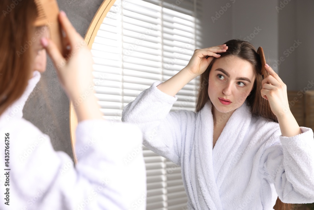 Beautiful woman combing her hair with healthy roots near mirror at home Beautiful woman combing her hair with healthy roots near mirror at home