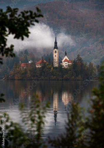 Assumption of mary pilgrimage church on lake bled, surrounded by mountains and colorful autumn foliage, in slovenia