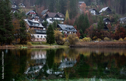 Houses reflecting in lake Jasna, slovenia during autumn in Julian alps