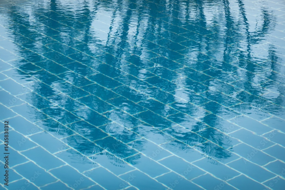 Swimming pool with blue water and palm trees reflected on surface