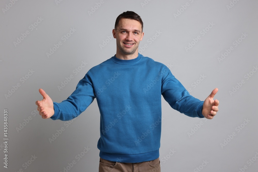 Cheerful man welcoming guests on light grey background Cheerful man welcoming guests on light grey background