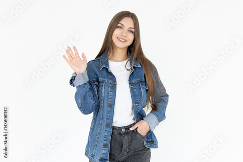 Cheerful friendly girl saying hello, winking and smiling, waving hand at camera, say hi and greet you, standing against white background