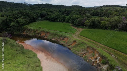 Serene river winding through green mountain valleys. Lush vegetation blankets the landscape. Peaceful flight over nature's beauty