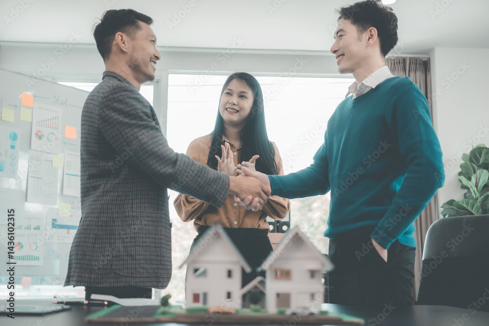Real estate businessmen shake hands to make an agreement to sell a house with a customer with a contract document.
