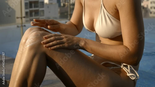 Sunlit relaxation by the poolside: woman applying lotion in golden hour