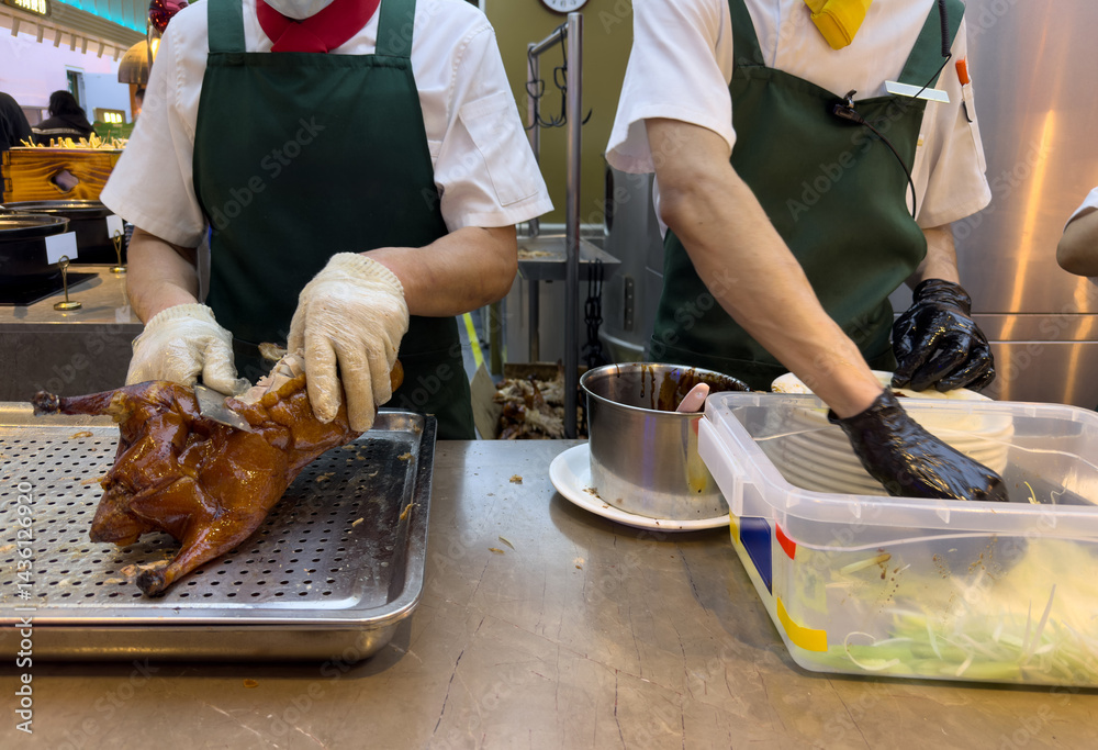 Peking duck preparation, Beijing restaurant, China. Chef carving meat with a sharp knife closeup on hands