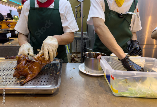 Obraz na płótnie Peking duck preparation, Beijing restaurant, China. Chef carving meat with a sharp knife closeup on hands w salonie