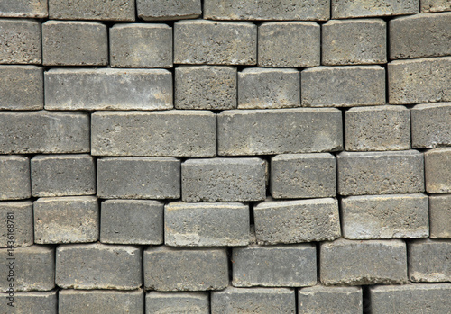 The surface of a wall or fence lined with gray bricks. Paving slabs of grey blocks of flat shape. Pavement blocks in city park. Park way materials. Bricks or blocks of paving slabs laid in row