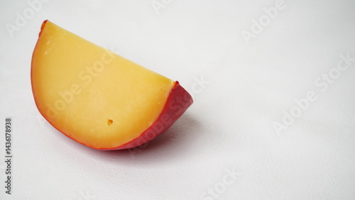 Chunk of aged edam cheese in hard red shell isolated on white background