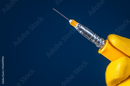 Obraz na płótnie A gloved hand holds a thin, silver needle attached to a yellow medical device against a dark blue background w salonie