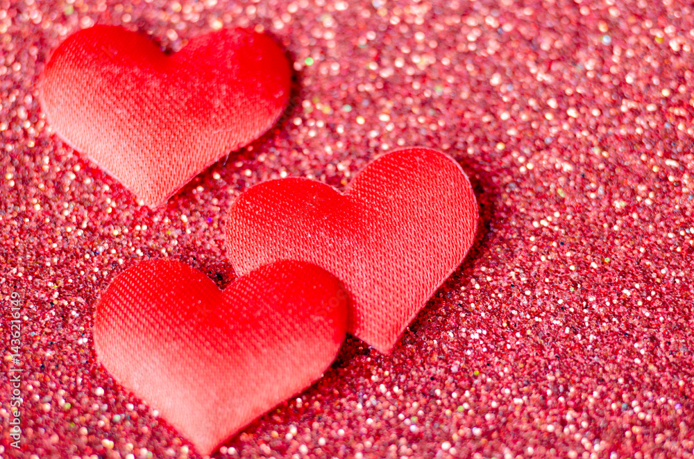Obraz premium Top view of 3 tiny red hearts on sparkle red background with customizable space for text or wishes.