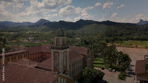 Drone captures a historic church and convent nestled amidst lush tropical mountains.