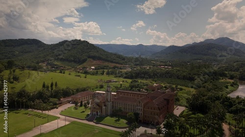 Drone captures a historic church and convent nestled amidst lush tropical mountains.