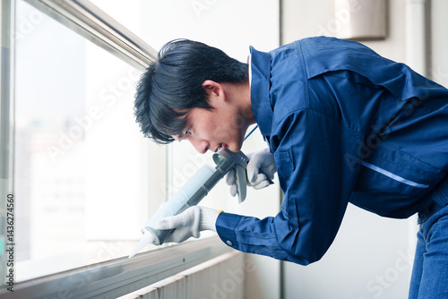 Fototapeta 外装工事でコーキング材を塗る作業員の男性