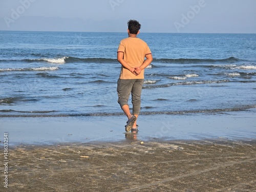A man walking on the beach, A man is walking on the beach, gazing at the ocean.