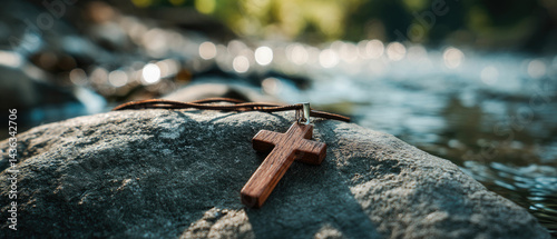 Wooden cross faith hope love religion necklace on rock by river water
