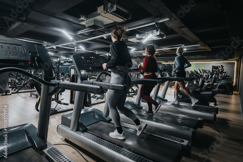 Obraz na płótnie Girls running on treadmills in a contemporary gym interior showcasing fitness, health, and exercise commitment. The image conveys an active and healthy lifestyle in a fitness-focused space. w salonie