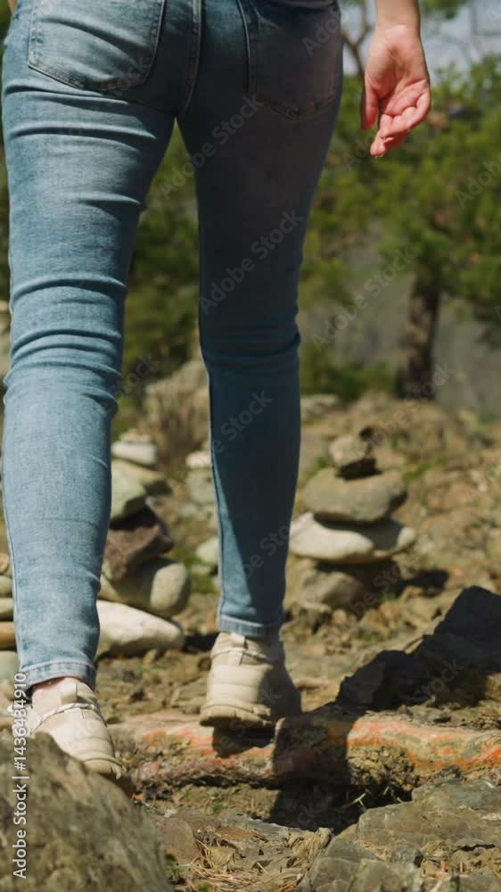 Tourist walks across glade with stacked rocks to pine wood backside view. Visiting place of spiritual energy. Altai country traditions Tourist walks across glade with stacked rocks to pine wood backside view. Visiting place of spiritual energy. Altai country traditions