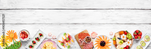 Obraz na płótnie Summer garden party food bottom border. Assortment of fun flower theme charcuterie items, cheese, fruit, vegetables and finger snacks. Top down view on a white wood banner background. w salonie