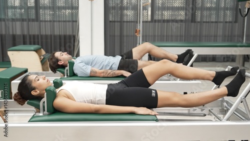 Φωτογραφία Couple practicing leg exercises on pilates reformer to strengthen core and improve flexibility at gym