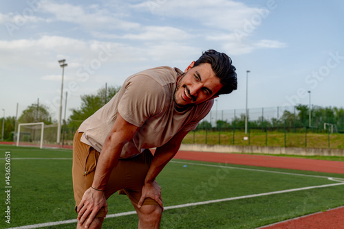 фотографія Exhausted male athlete resting on a stadium track, catching breath after an inte