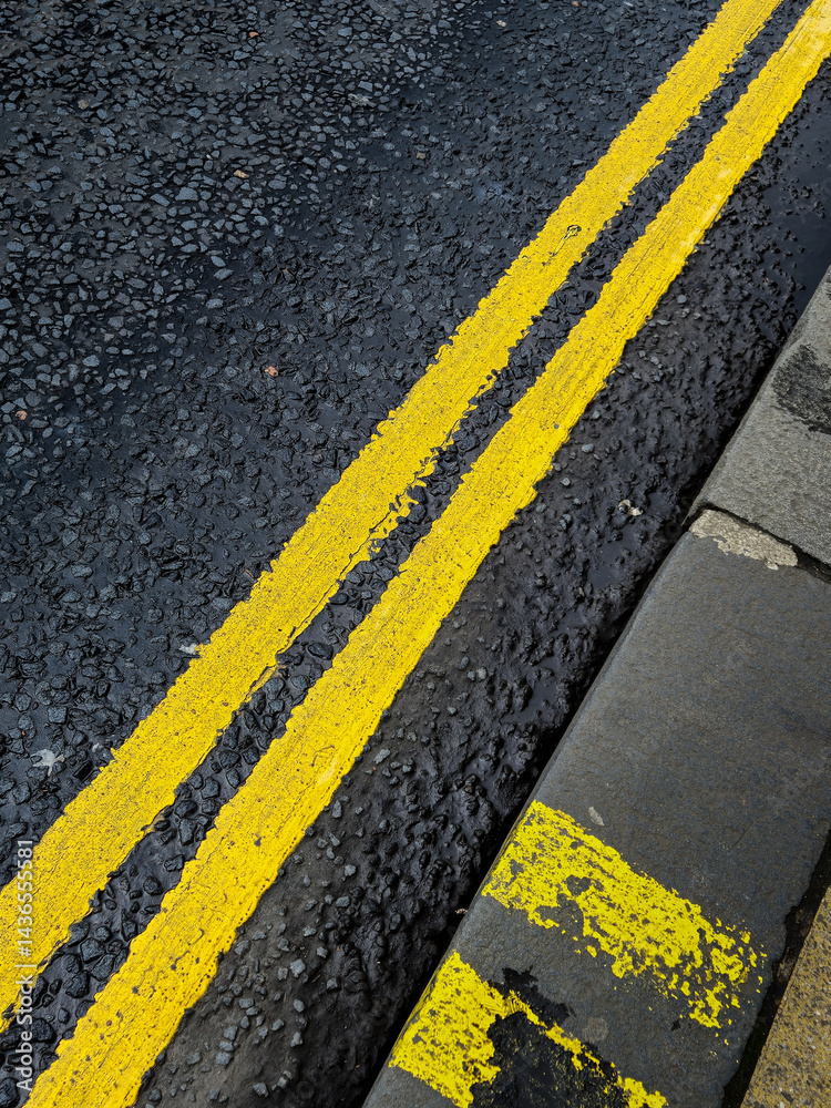 Fototapeta premium A yellow line is painted on a black road