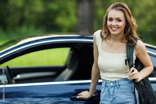 Obraz na płótnie Happy woman driver gets car with backpack. Cute young happy brunette female driving car vehicle w salonie
