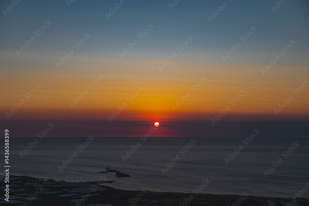 Fototapeta premium The sun at orange sunset just above the surface of the sea