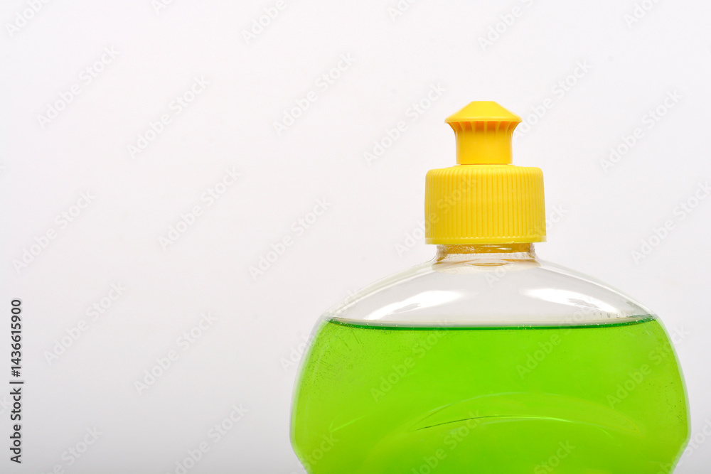 A close-up shot shows a clear plastic bottle filled with bright green dish soap and capped with a yellow lid