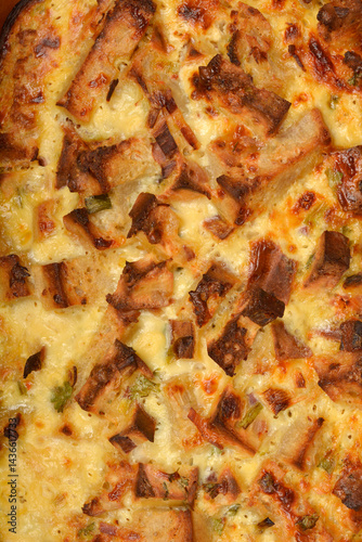 Obraz na płótnie A close-up shot reveals the golden-brown, bubbly surface of a freshly baked strata (layered casserole dish made from a mixture which mainly consists of bread, eggs and cheese) w salonie