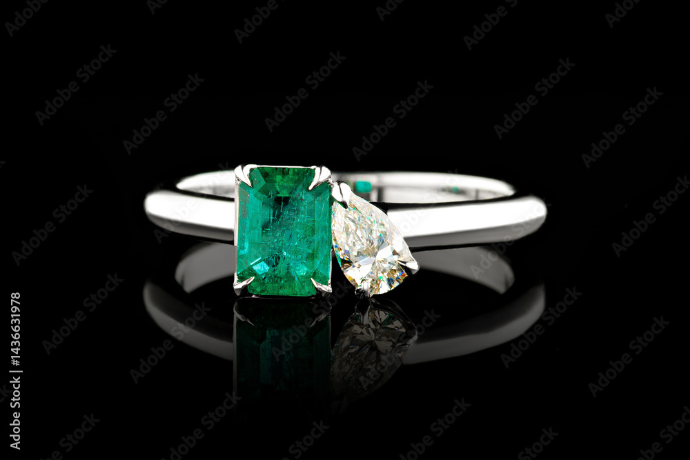 silver or gold ring with emerald stone and diamonds on black background