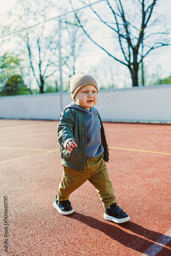 Obraz na płótnie Toddler boy running outside with soap bubbles. Child on a warm spring day for a walk in a jacket and hat. w salonie