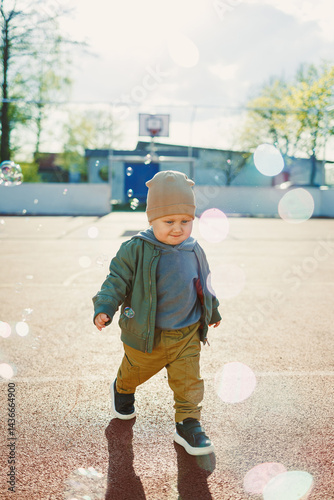 Obraz na płótnie Little cute boy 2 years old running with soap bubbles. Boy catching soap bubbles in the park, enjoying a sunny summer day. Creative activities for children outdoors w salonie