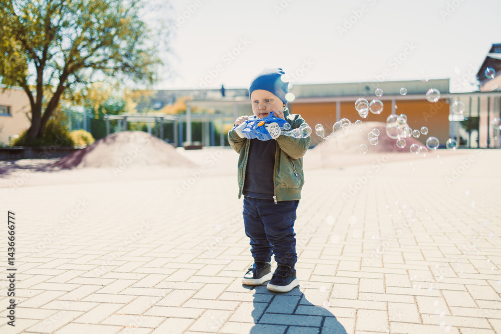 Little cute boy 2 years old running with soap bubbles. Boy catching soap bubbles in the park, enjoying a sunny summer day. Creative activities for children outdoors