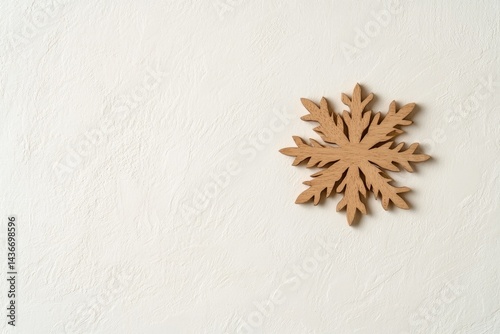 Delicate wooden snowflake design against soft white background,