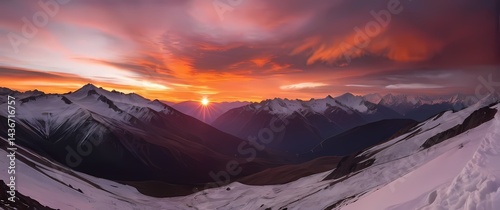 Dramatic sunset over serene mountain valley tinging snow capped peaks in hues of flaming orange and pink photo