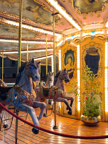vintage carousel horses illuminated at night in Florence, Italy. ornate decorations and warm festive lights. nostalgic charm of traditional amusement