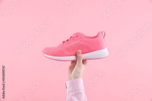 Woman with stylish sneaker on pink background, closeup