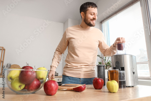 Young man making apple juic...