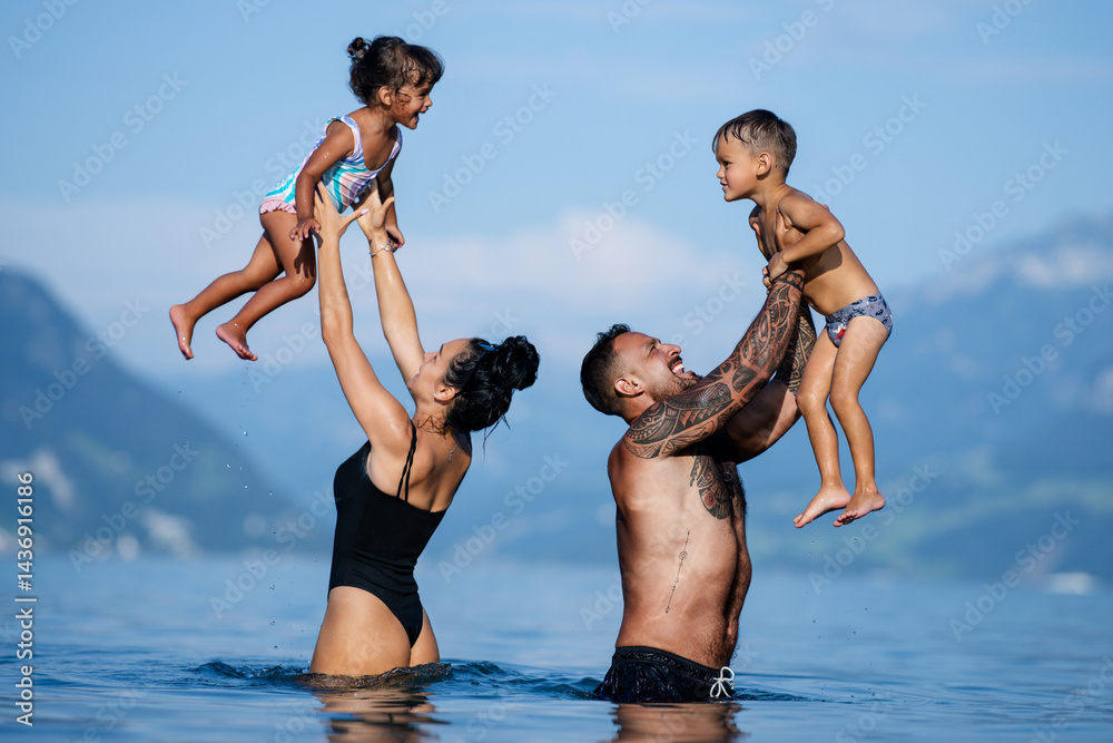 Happy family on summer. Mom and dad play with son and daughter. Loving family play on beach. Father and mother lift son and daughter up. Family summer vacation. Summer family travel.