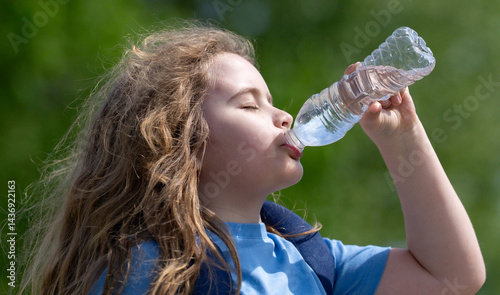 Child drinking water from bottle. Kid refreshing with drink. Thirsty child drink water from plastic bottle. Close-up of thirsty kids face. Fresh water in nature. Pure water bottle for thirsty kid.