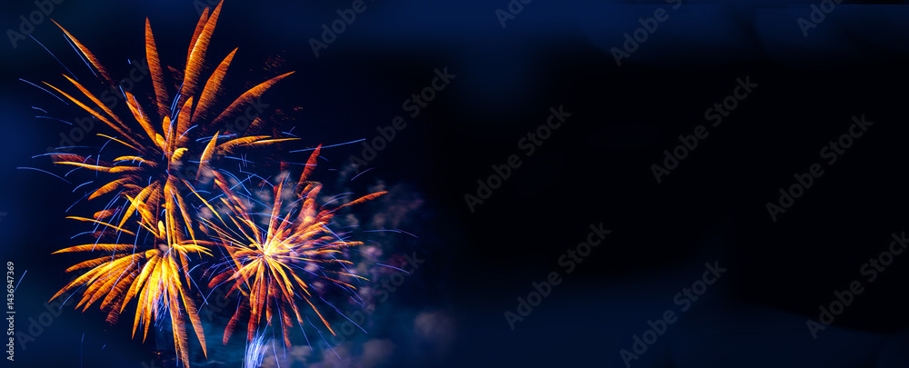 Brilliant orange and blue fireworks against a deep black night sky with copy space for festive or celebratory themes