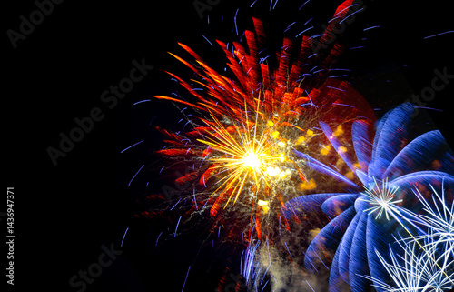Obraz na płótnie Brilliant orange, yellow and blue fireworks against a deep black night sky with copy space for festive or celebratory themes w salonie